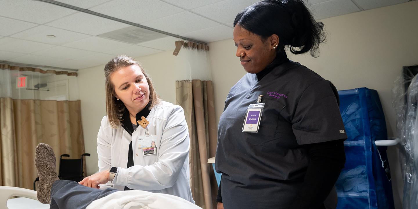 Young woman student with a woman doctor treating a patient in a hospital setting.