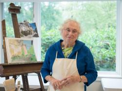 An Orchard Cove resident takes a break from painting in a sunny art studio.
