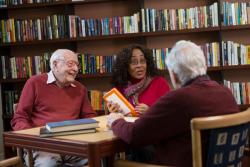 Two residents chat with a woman in the CCB library.
