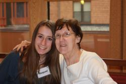 An older woman with her arm around a teenage girl. They are smiling at the camera.