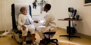 Older woman sitting in doctor office chair seeing a woman doctor