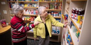 Two older women in a shop looking at items on shelves