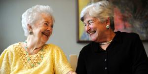 Two older women sitting together smiling.
