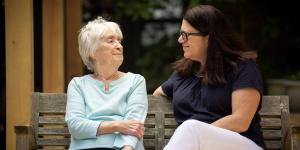 Older woman sitting on a bench with another woman