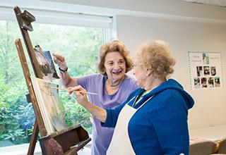 Two women Orchard Cove residents paint together.