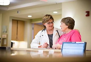 A female doctor leans in to talk to a woman