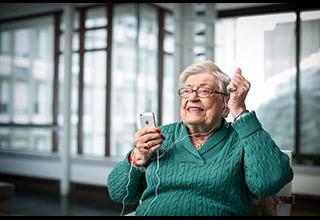 An older woman listens to music on an iPod.
