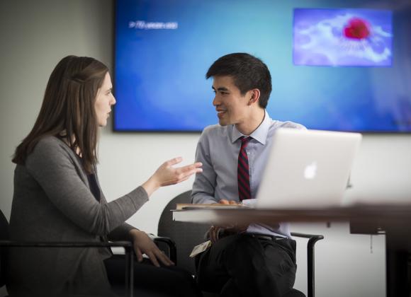 A man and a woman researcher review data on a laptop.