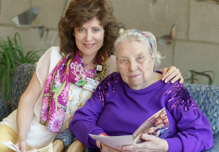 Russian Bilingual Program Director Alexandra Dashevskaya sits with her arm around a patient at Hebrew Rehabilitation Center in Boston.