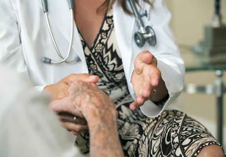 Close up of a doctor holding the hand of a patient.