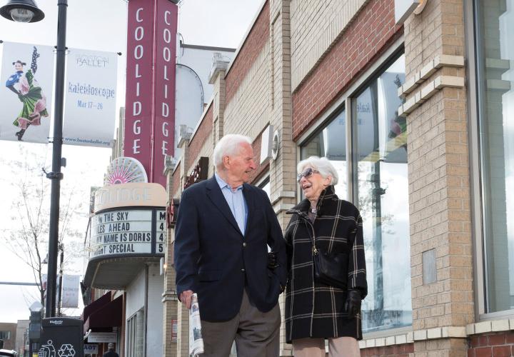 An older couple takes a fall stroll on Beacon Street, passing the iconic Coolidge Corner theatre.