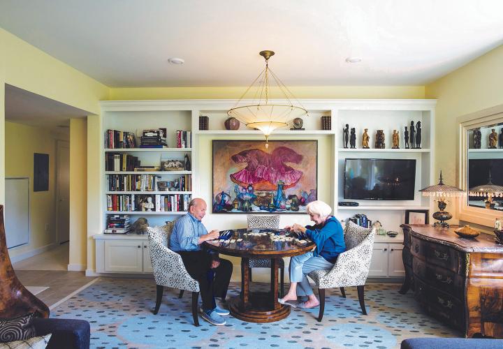 A couple enjoy a game in the library of their villa residence at NewBridge on the Charles.