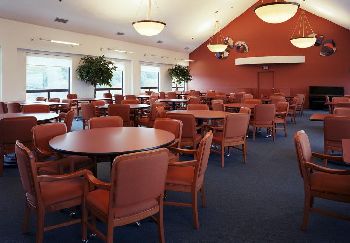 Dining room at 100 Centre Street, filled with red chairs and tables and low-hanging lights