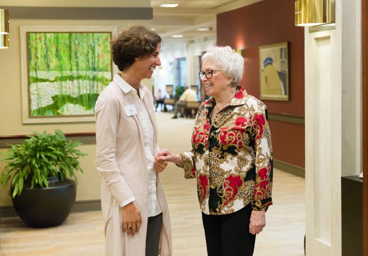 Orchard Cove's executive director chats with older woman in the Orchard Cove main lobby.