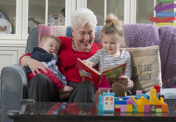 Happy grandmother, an HSL resident, reading to grandson and granddaughter