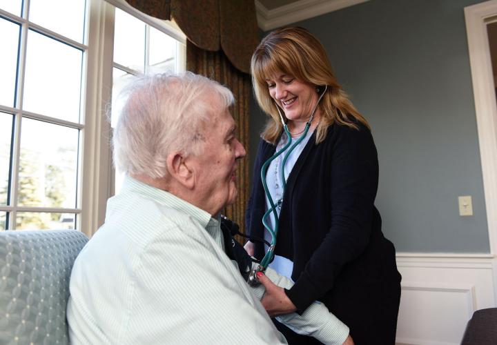 A Hebrew SeniorLife home health worker listens to a client's heart with a stethoscope.