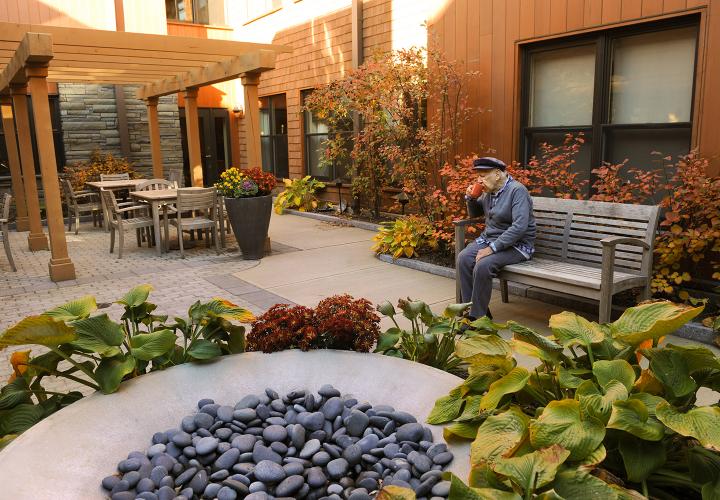 A resident of memory care assisted living at NewBridge on the Charles enjoys a quiet moment in one of two secure outdoor courtyards.