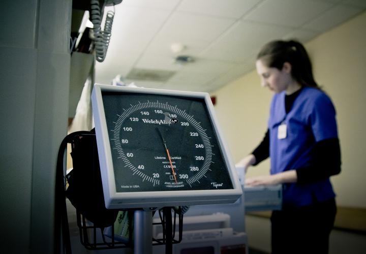 Nurse looking up documentation on the Medical Acute Care Unit with blood pressure monitor in foreground