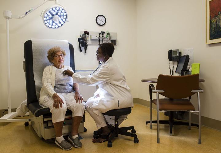 A Hebrew SeniorLife doctor listens to the heartbeat of a community resident in an exam room