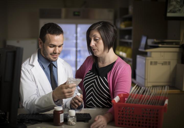 A female pharmacist and a male pharmacy student standing in the pharmacy at Hebrew Rehabilitation Center in Boston.