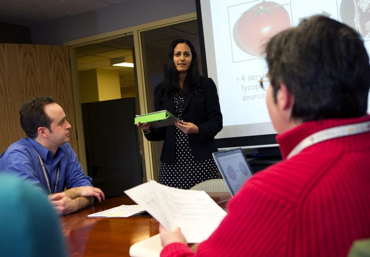 A researcher at the Marcus Institute stands in front of a screen presenting to two other researchers.
