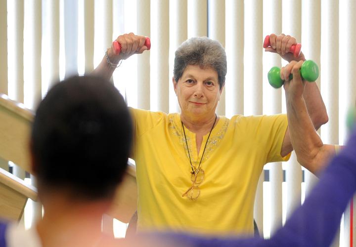 Two Simon C. Fireman Community residents lifting weights in an exercise class with instructor