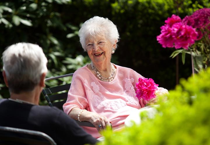 Older woman in garden laughing with friend