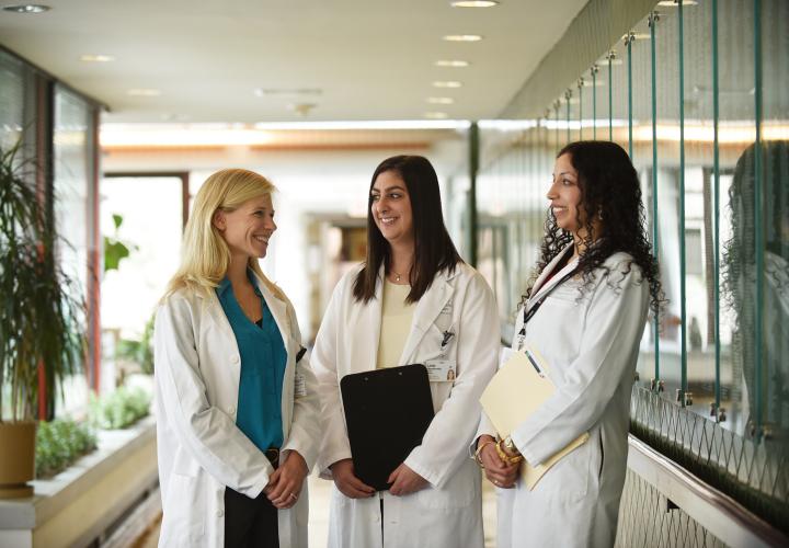 Three female doctors from the Harvard Medical School geriatric fellowship standing in a hall at Hebrew Rehabilitation Center in Boston.