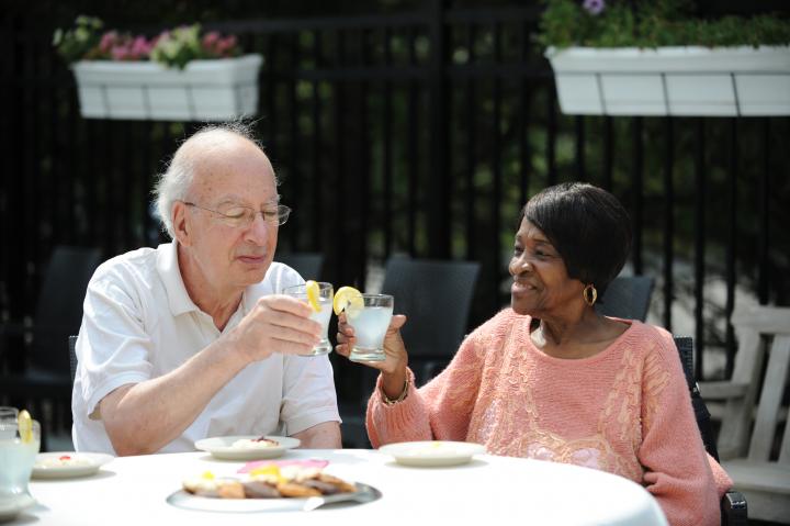Two adult day health participants raise glasses in a toast to the newly opened patio in Roslindale.