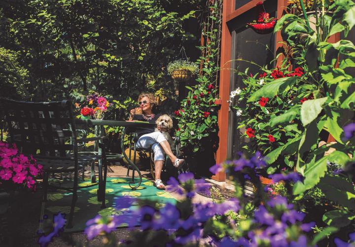 A NewBridge resident enjoys a cup of coffee on her garden patio, with pet dog on her lap.