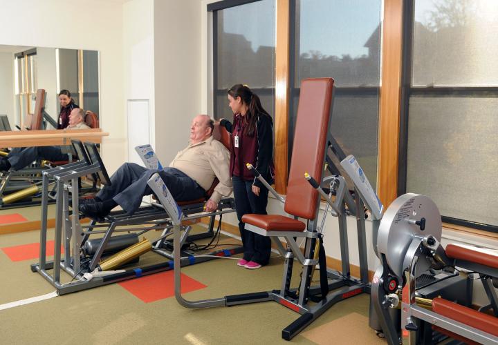 An assisted living resident of NewBridge the Charles receives personal training in our gym designed for geriatric fitness