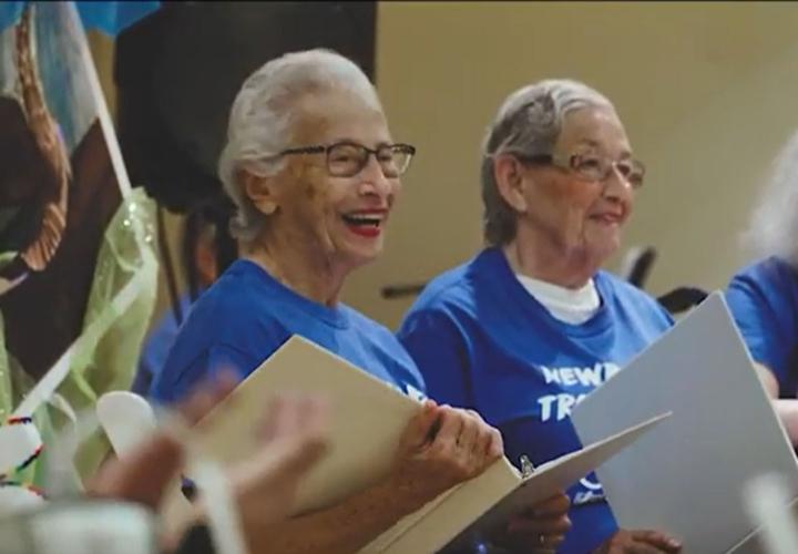 Memory Care Assisted Living resident Martha Korman smiles as she sings with a group of residents.