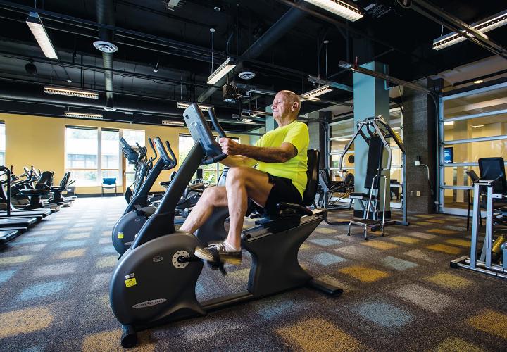A resident of NewBridge on the Charles works out in the spacious fitness center filled with equipment designed for geriatric exercise. 