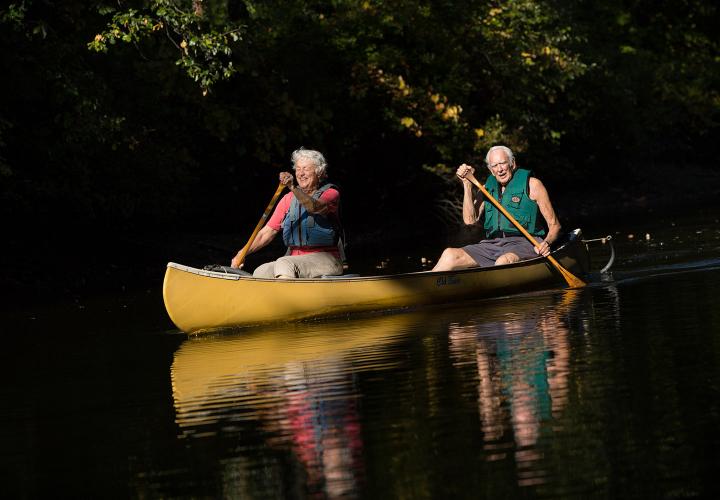 An older couple enjoys an afternoon of canoeing on the Charles River thanks to the NewBridge on the Charles boat launch connecting the campus to the Dedham Water Trail.