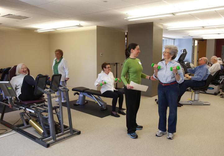 Orchard Cove's fitness center bustles with activity as residents use the equipment and talk with a fitness consultant.