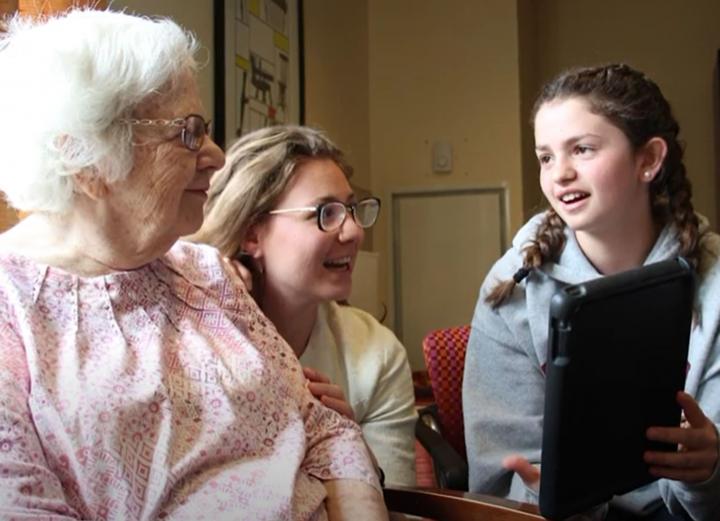 A mother and young daughter visit with a patient.