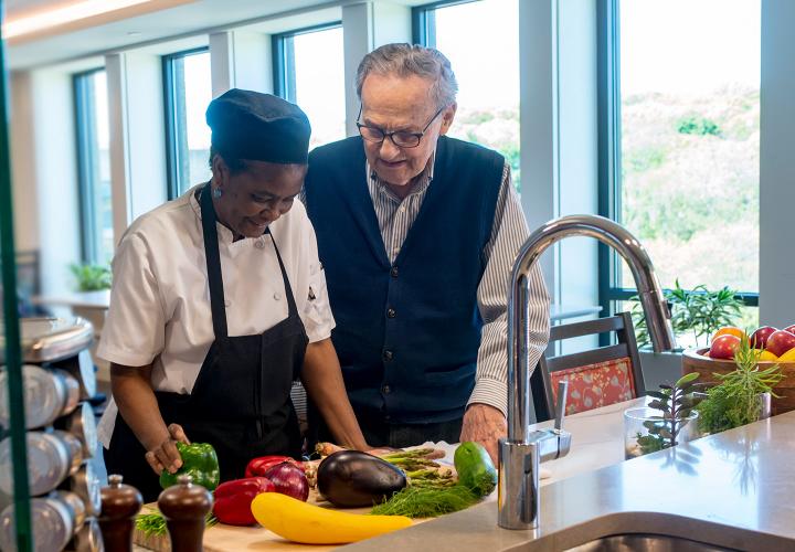 A culinary staff member with a patient at Hebrew Rehabilitation Center in Boston. They are standing in front of a counter that is filled with colorful vegetables.