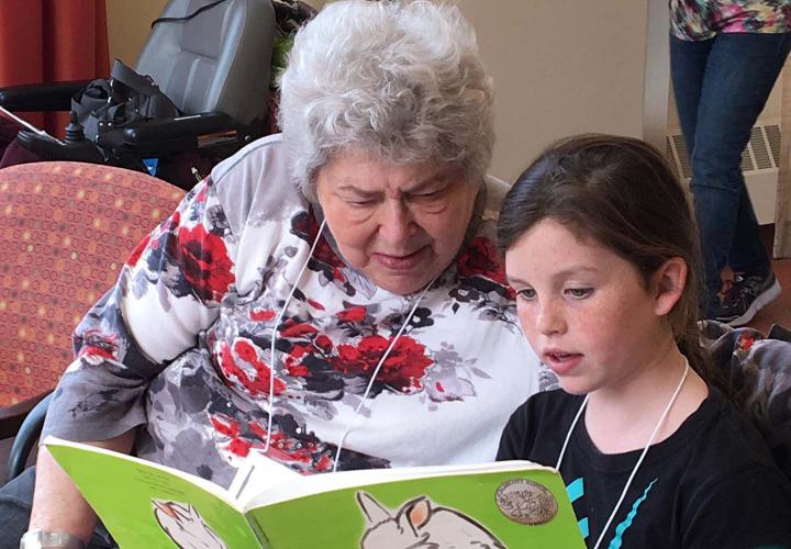 A senior woman and a child read a book together.