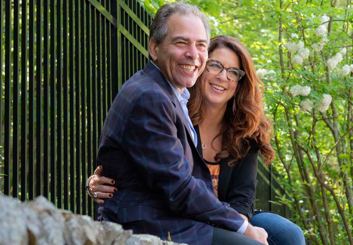 HSL donors Rick and Gabrielle Henken sit on a stone wall in a park.