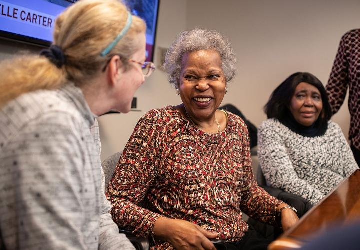 Three women sit chatting and laughing at Simon C. Fireman Community in Randolph, MA.