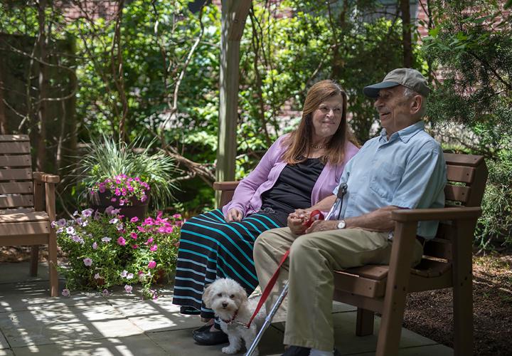 Older man and woman sitting outside with dog