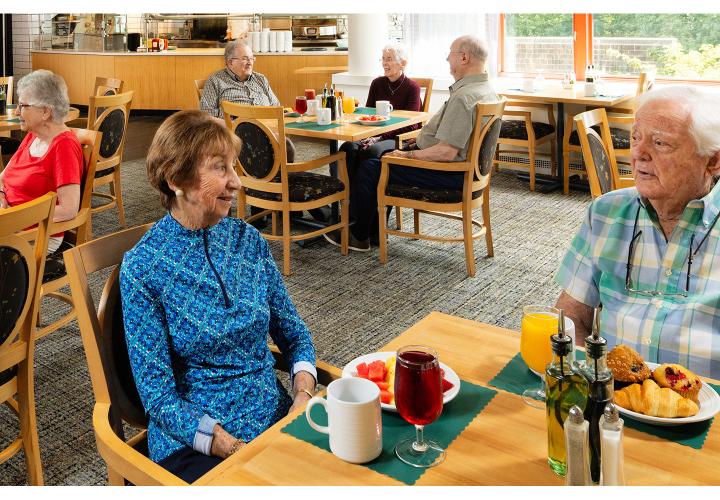 A wide shot of older men and women eating in a dining room