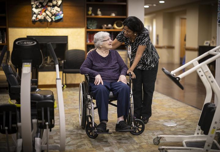 A patient care assistant talks with an older patient.
