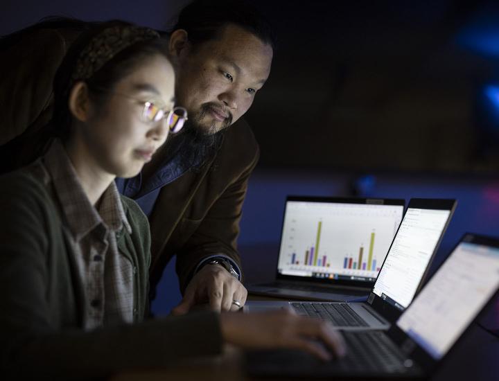 A male and a female researcher review data on a computer screen.