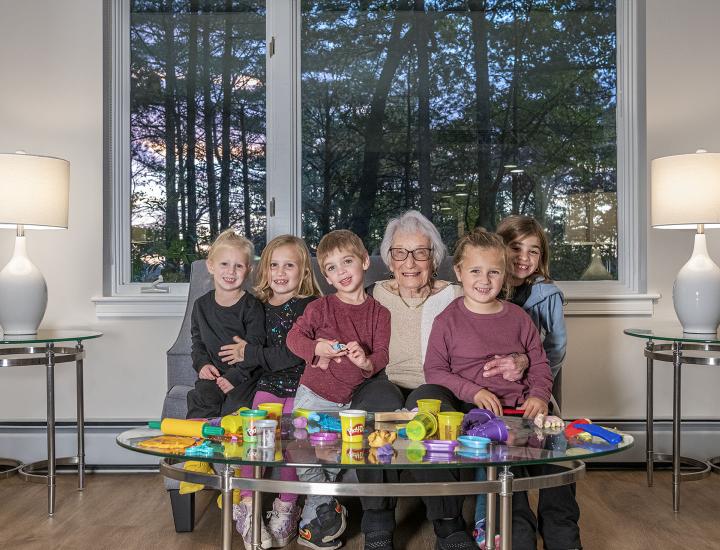 A grandmother sits with all of her grandchildren.