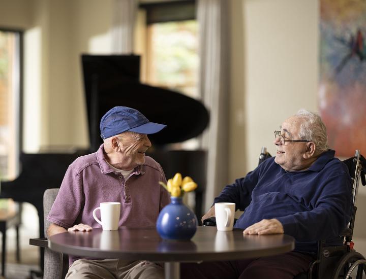 Two older gentleman sitting at a table and enjoying a conversation.