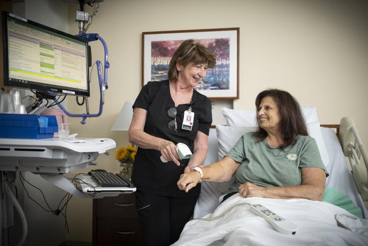 A female nurse scans a female patient's wrist band.
