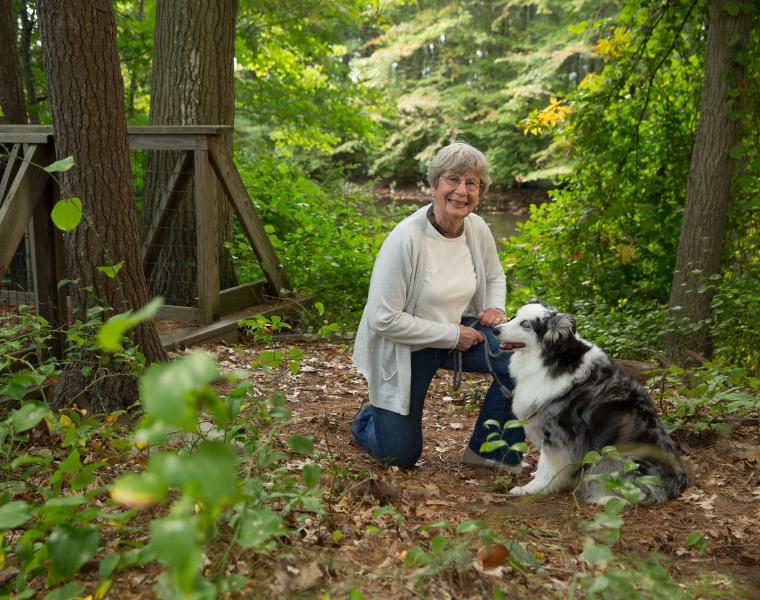 An Orchard Cove resident walks her dog on one of the many wooded trails surrounding the community.