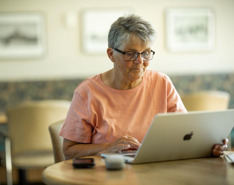 An older woman works on her laptop.