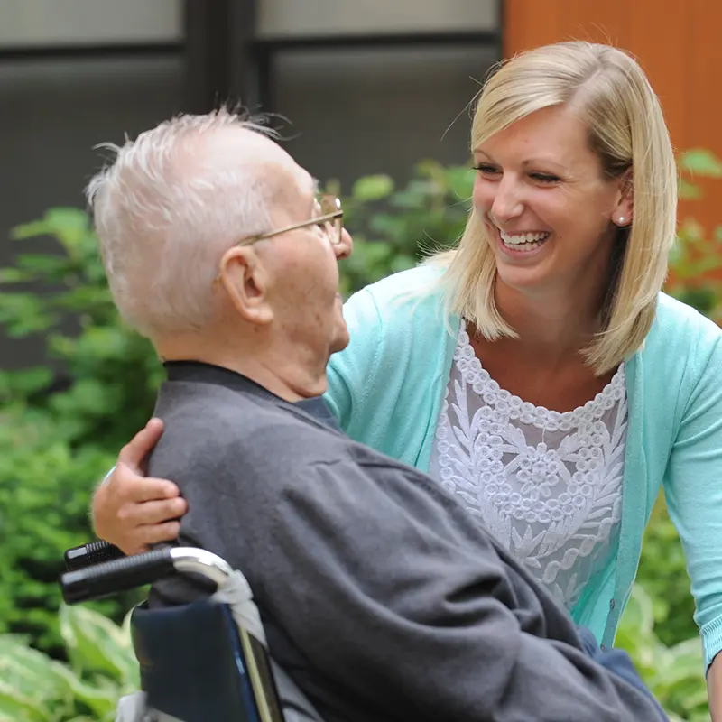 an older man in a wheelchair sharing a smile with a younger woman